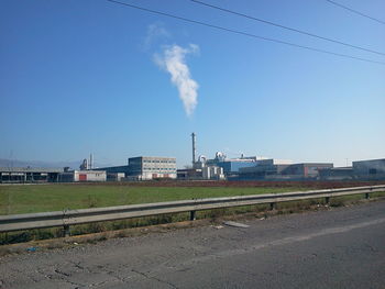 Smoke emitting from factory against blue sky