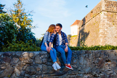 Full length of woman sitting against wall