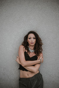 Portrait of beautiful young woman standing against wall