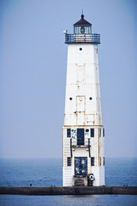 Lighthouse by sea against sky