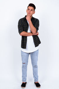 Portrait of young man standing against white background