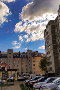 Cars on road by buildings against sky