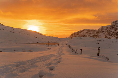 Scenic view of snowcapped mountains against orange sky