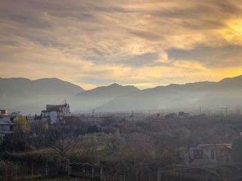 Houses in town against sky during sunset
