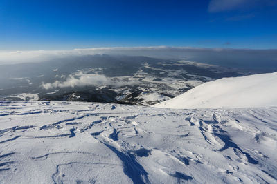 Scenic view of snow covered mountains against blue sky