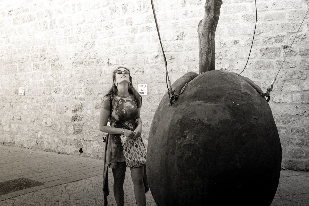 FULL LENGTH OF WOMAN STANDING BY WALL