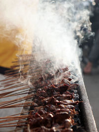Close-up of meat on barbecue grill. the seller is grilled satay.