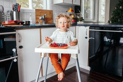 Baby boy eating ripe red fruits at home. supplementary healthy finger food for toddler kids.