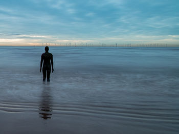 Full length of man standing on beach against sky