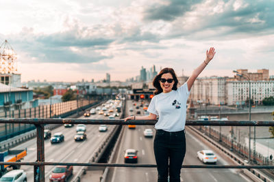 Portrait of woman standing by railing in city