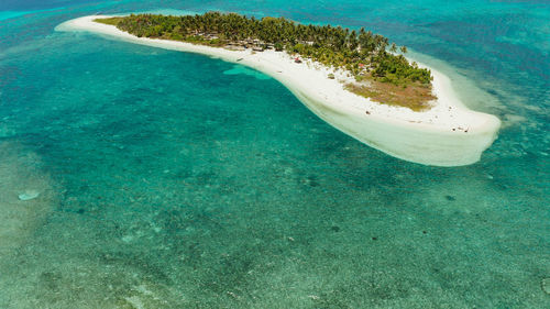 Small tropical island in the blue sea with a coral reef and the beach, top view. canimeran island