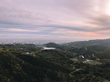 Aerial view of green landscape against cloudy sky during sunset