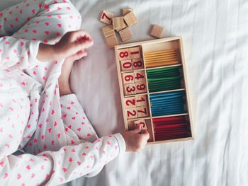 High angle view of child arranging blocks with number in box on bed