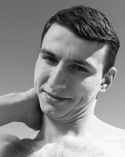 Close-up portrait of a smiling young man against gray background