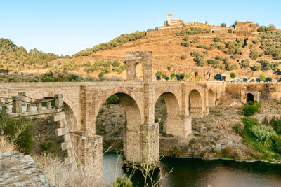 Arch bridge over river against sky