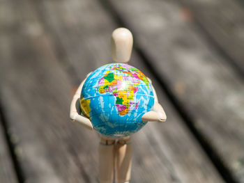 Close-up of wooden figurine holding globe on table