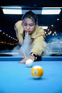 Portrait of young woman playing pool