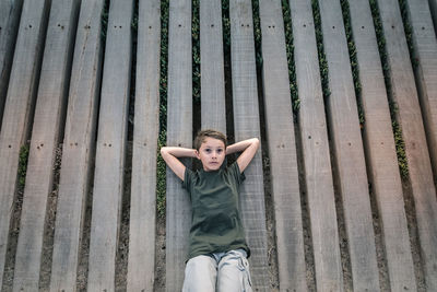 High angle view of boy lying on wooden planks