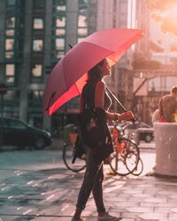 Full length of woman with umbrella walking in city during rainy season