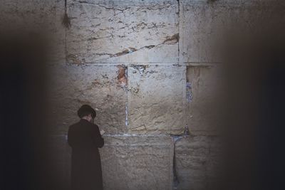 Rear view of woman standing against wall