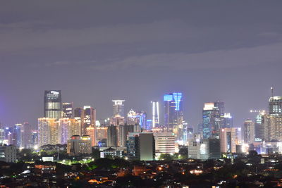 Illuminated buildings in city against sky at night