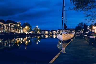 Boats moored on illuminated city at night