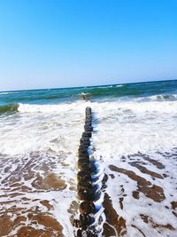 High angle view of groyne in sea against clear blue sky