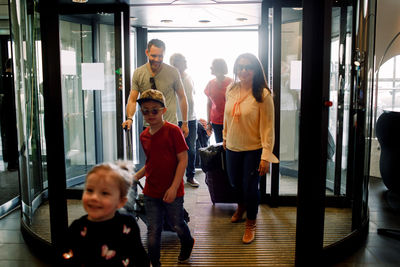 Smiling family entering hotel during vacations