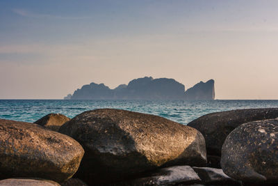 Rocks on beach against sky during sunset