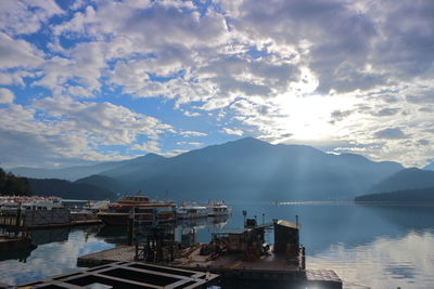 Scenic view of bay and mountains against cloudy sky