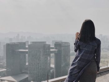 Rear view of young woman on terrace against cityscape