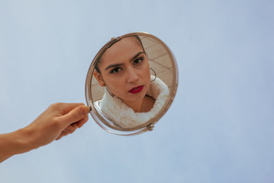 Cropped hand of woman holding mirror in city