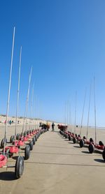 Cars on road by sea against clear blue sky