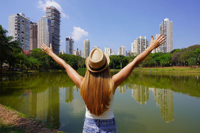 Back view of girl with raising arms in the city park vaca brava in goiania, goias, brazil.