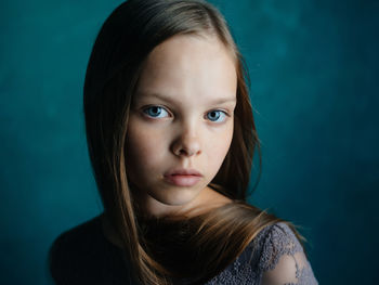 Close-up portrait of teenage girl against blue background