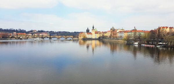 Bridge over river by buildings against sky