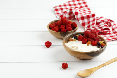 Homemade greek yogurt with raspberry and dried fruit, copy space for text on white background