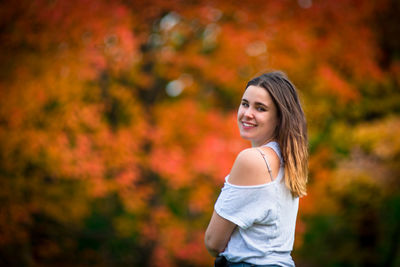 Portrait of smiling young woman standing during autumn