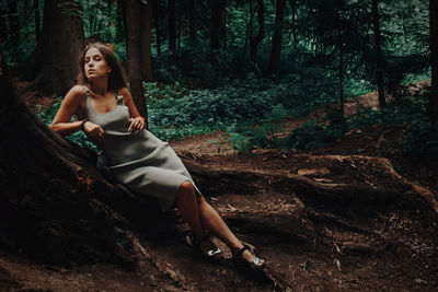 Young woman sitting on tree trunk in forest