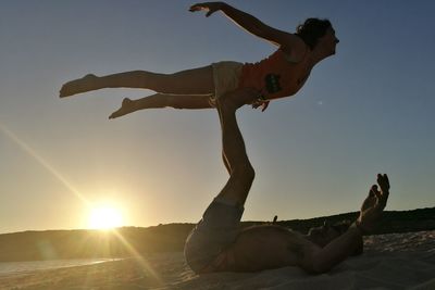 Low angle view of couple kissing against sky during sunset