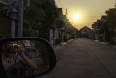 Reflection of man photographing car on side-view mirror