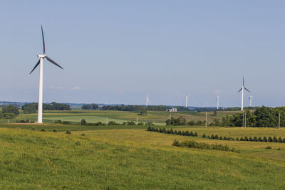 Wind turbines on field against clear sky