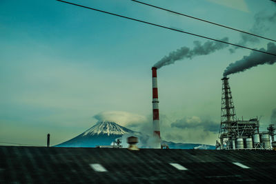 Smoke emitting from factory against sky