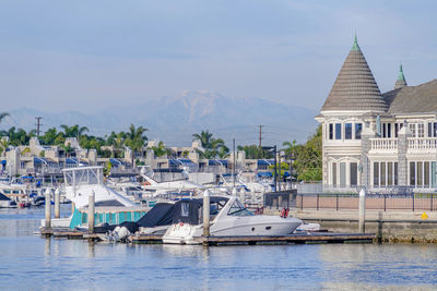 Sailboats moored in sea against buildings