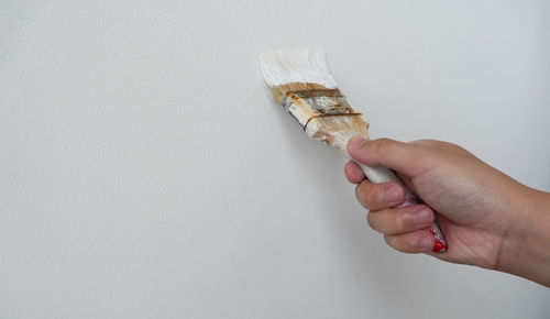 Close-up of hand holding ice cream over white background