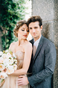 Portrait of young couple standing against wall