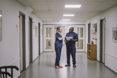 Male and female medical staff discussing while standing in corridor at healthcare center