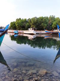 Boats moored on lake against sky