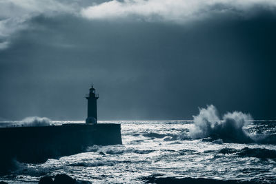 Lonely lighthouse standing agains stormy sea in the evening