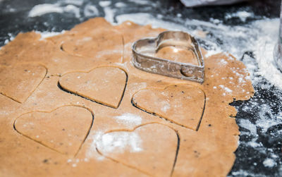 Close-up of heart shape pastry cutter cutting dough on table